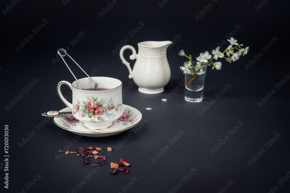 Fototapeta premium Still life with a beautiful fine china tea cup and tea accessories on a black background
