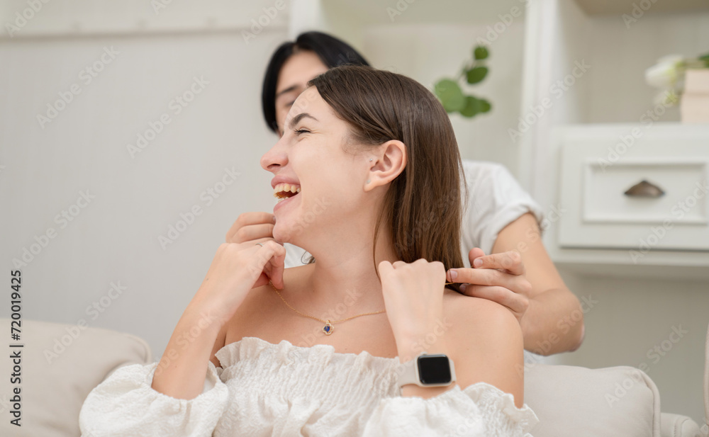 A young man putting around his Surprise gift girlfriend's Valentine's Day concept. Lovers at home celebrating Valentine's Day. A young man putting around his Surprise gift girlfriend's Valentine's Day concept. Lovers at home celebrating Valentine's Day.