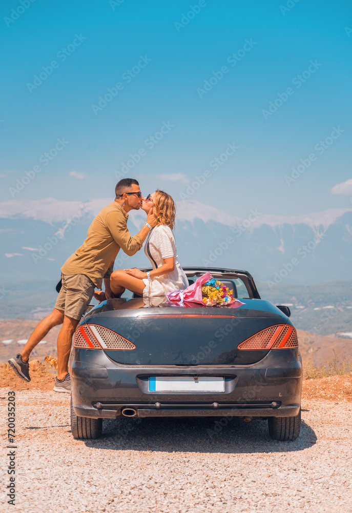 Happy newlyweds on their honeymoon in a beautiful convertible car posing against the backdrop of the mountains. Newlyweds travel on their honeymoon to fantastic places in Turkey.