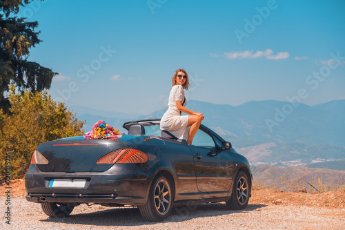 Happy newlyweds on their honeymoon in a beautiful convertible car posing against the backdrop of the mountains. Newlyweds travel on their honeymoon to fantastic places in Turkey.