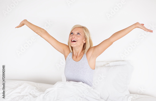 Morning stretching, bedroom and wake up with woman, relax after sleeping or resting. Blanket, peace and comfort of happy person stretch after sleep feeling fresh, awake or joyful with girl or home photo