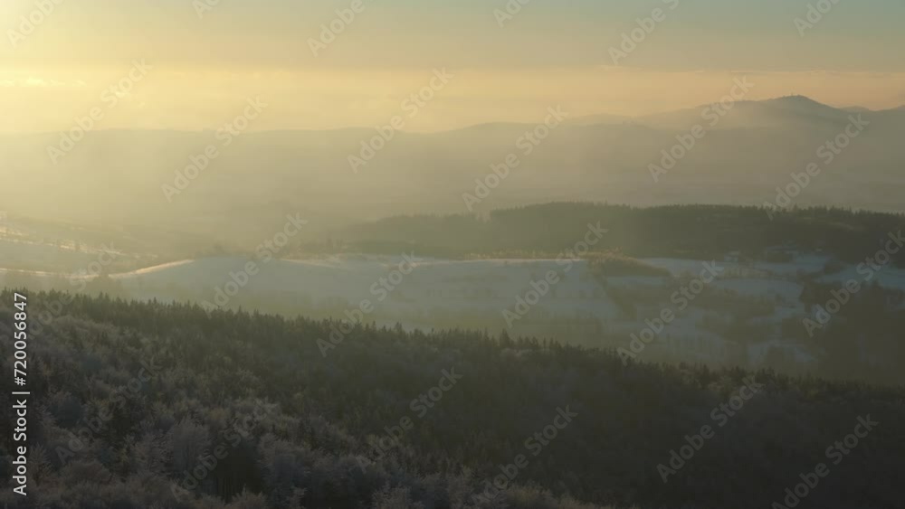 Aerial view of a mountain sunset, with snow-blanketed trees and rapidly moving clouds, creating a serene yet dramatic scene. Aerial view of a mountain sunset, with snow-blanketed trees and rapidly moving clouds, creating a serene yet dramatic scene.