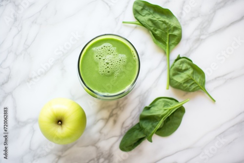 an overhead shot of a green juice with green apple slices on top