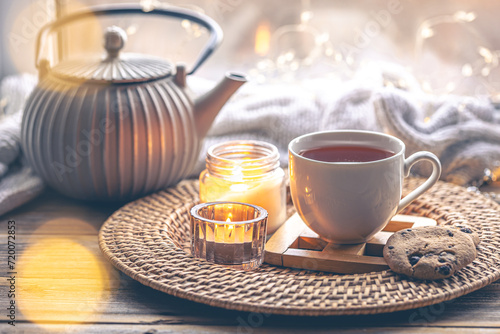 Cozy home composition with a cup of tea, candles and a teapot.