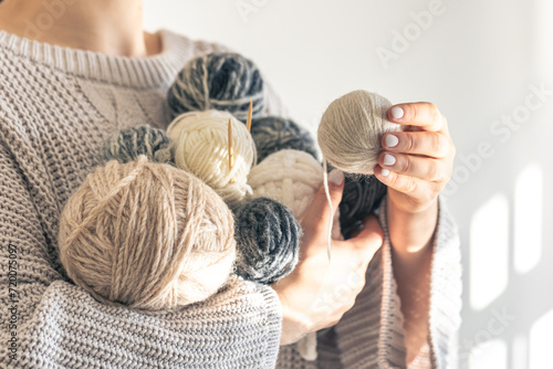 Close-up, woman hands holding several colored balls of thread.