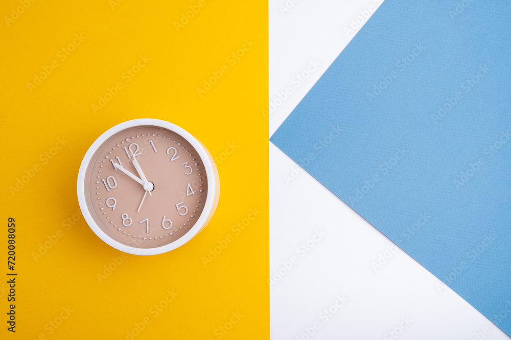 White alarm clock on a colored background. Fashionable minimalist style. Time, business and technology concept. Flat composition. View from above White alarm clock on a colored background. Fashionable minimalist style. Time, business and technology concept. Flat composition. View from above