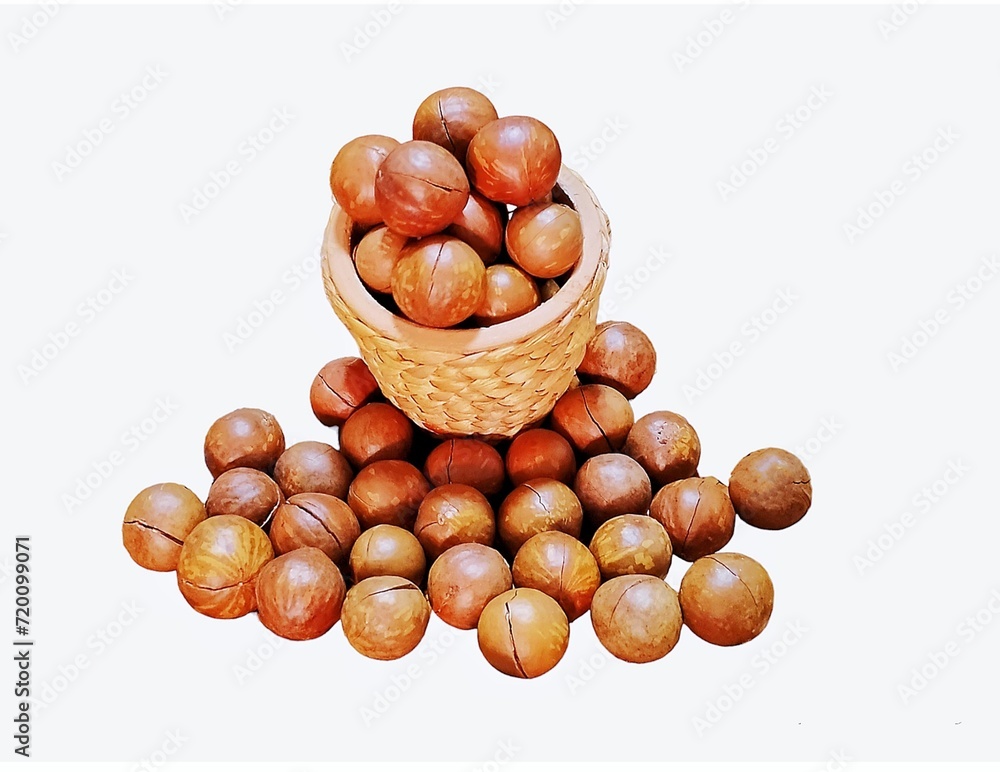 Here are some macadamia nuts in a brown wicker basket, and some on the ground nearby. Macadamia nuts have brown skins, white insides, and are cooked by roasting. If they are ripe, It will be white, Here are some macadamia nuts in a brown wicker basket, and some on the ground nearby. Macadamia nuts have brown skins, white insides, and are cooked by roasting. If they are ripe, It will be white,