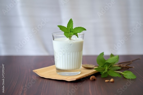 glass of coconut milk with a splash and mint leaf on top photo