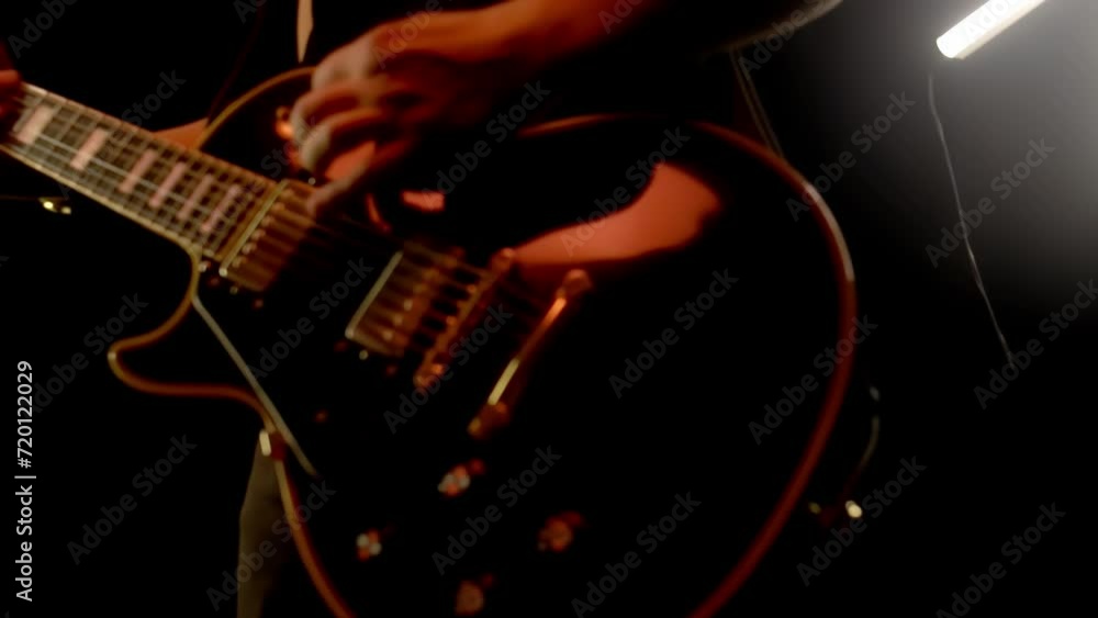 Guitarist plays electric bass guitar in slow motion, close up body and