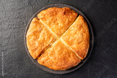 Bakery. Delicious Homemade cheese pie with pastry. Bulgarian banitsa. Traditional Romanian baked house pie with cheese. Burek pie with cheese stuffing. Greek feta pie on dark background. Top view.