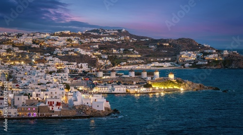 Fototapeta Naklejka Na Ścianę i Meble -  Aerial view of the illuminated old town of Mykonos island until the famous windmills during evening, Cyclades, Greece