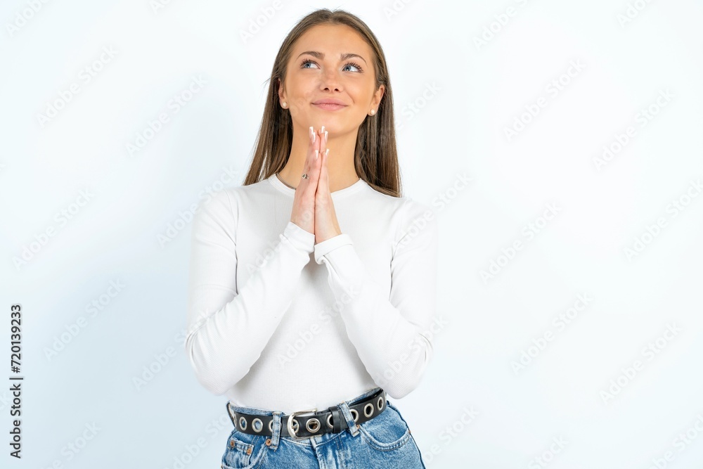 young beautiful caucasian woman wearing white long sleeve T-Shirt begging and praying with hands together with hope expression on face very emotional and worried. Please God young beautiful caucasian woman wearing white long sleeve T-Shirt begging and praying with hands together with hope expression on face very emotional and worried. Please God