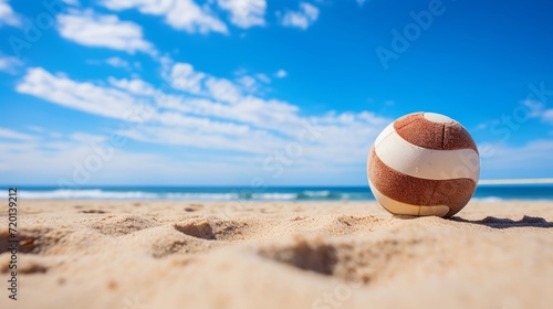 Volleyball left on a sandy beach under a clear blue sky on a sunny day.