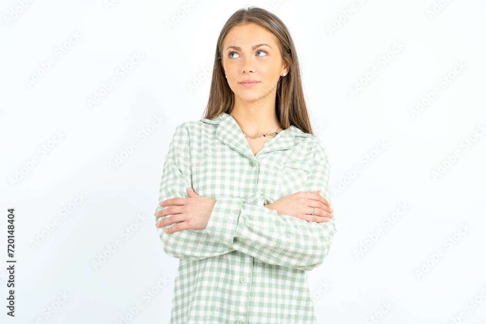Charming thoughtful Beautiful young woman wearing green plaid pyjama stands with arms folded concentrated somewhere with pensive expression thinks what to do Charming thoughtful Beautiful young woman wearing green plaid pyjama stands with arms folded concentrated somewhere with pensive expression thinks what to do