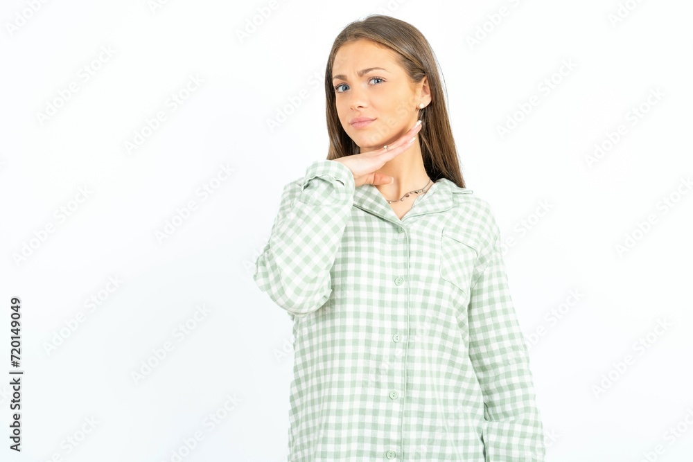 Beautiful young woman wearing green plaid pyjama cutting throat with hand as knife, threaten aggression with furious violence. Beautiful young woman wearing green plaid pyjama cutting throat with hand as knife, threaten aggression with furious violence.