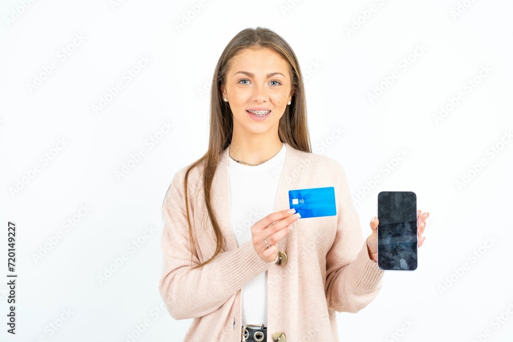 Photo of adorable beautiful girl wearing casual clothes holding credit card and Smartphone. Reserved for online purchases Photo of adorable beautiful girl wearing casual clothes holding credit card and Smartphone. Reserved for online purchases