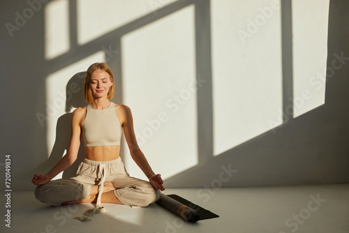 Woman practicing yoga and meditation in lotus pose on yoga mat, relaxed. Mindful meditation concept. Wellbeing