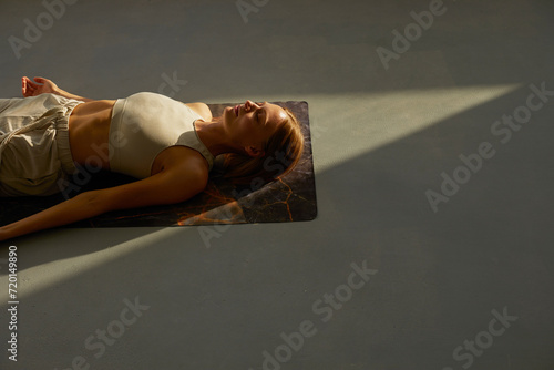 Young woman practicing corpse asana in yoga studio. Savasana pose.
