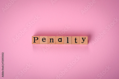 The inscription Penalty made up of wooden cubes on a plain background