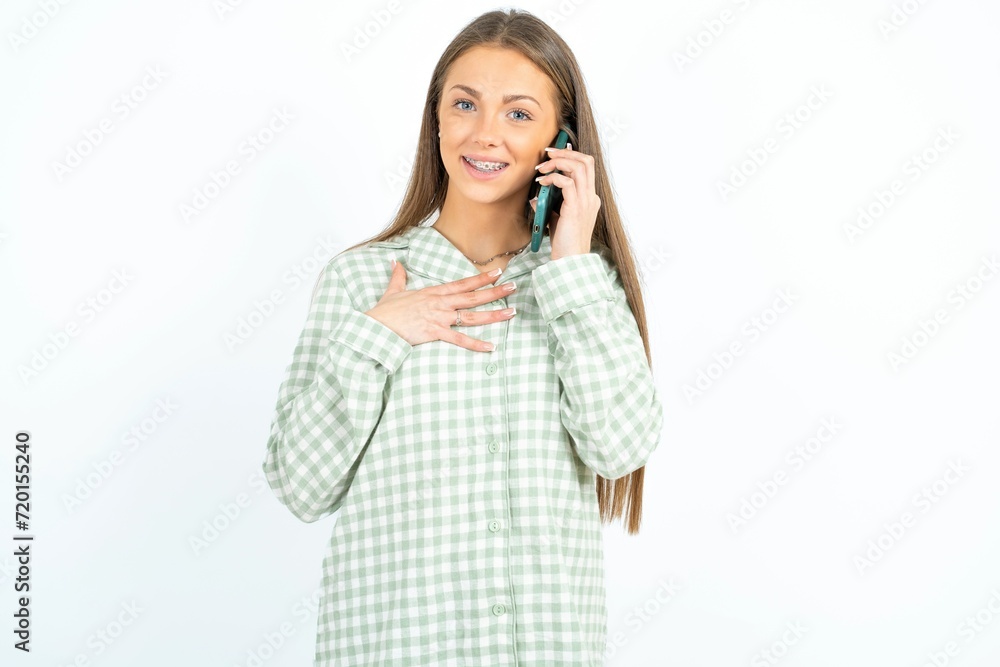 Smiling Young beautiful woman standing over white studio background talks via cellphone, enjoys pleasant great conversation. People, technology, communication concept Smiling Young beautiful woman standing over white studio background talks via cellphone, enjoys pleasant great conversation. People, technology, communication concept