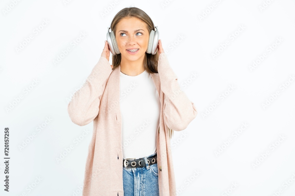 Joyful Young beautiful woman sings song keeps hand near mouth as if microphone listens favorite playlist via headphones Joyful Young beautiful woman sings song keeps hand near mouth as if microphone listens favorite playlist via headphones
