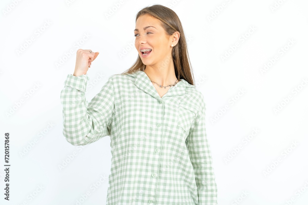 Portrait of funny young beautiful woman wearing green plaid pyjama, shout yeah raise fists hands celebrate victory game competition Portrait of funny young beautiful woman wearing green plaid pyjama, shout yeah raise fists hands celebrate victory game competition