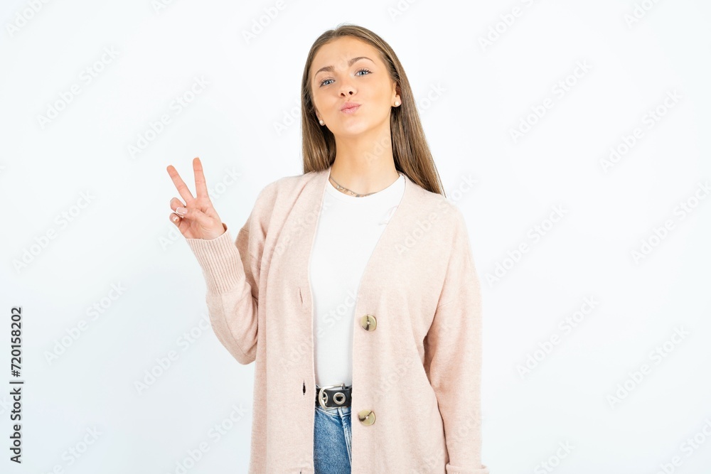 Young beautiful woman makes peace gesture keeps lips folded shows v sign. Body language concept Young beautiful woman makes peace gesture keeps lips folded shows v sign. Body language concept