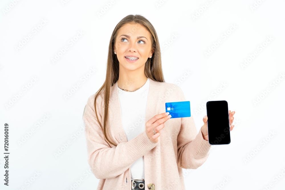 Young beautiful woman holding bank card modern device looking empty space Young beautiful woman holding bank card modern device looking empty space