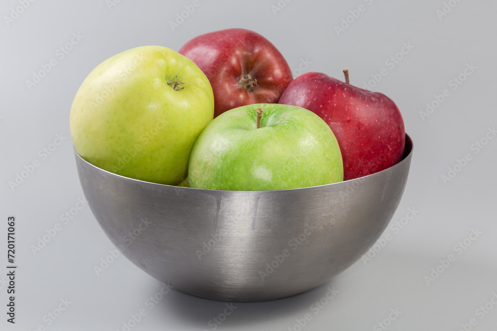 Apples different colors in bowl on gray background, side view Apples different colors in bowl on gray background, side view