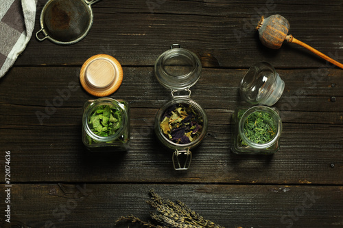 Dry herbs in glass jars on a wooden table