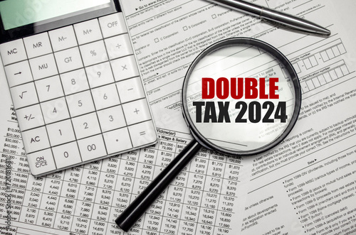 DOUBLE TAX 2024 word on magnifying glass with calculator and documents