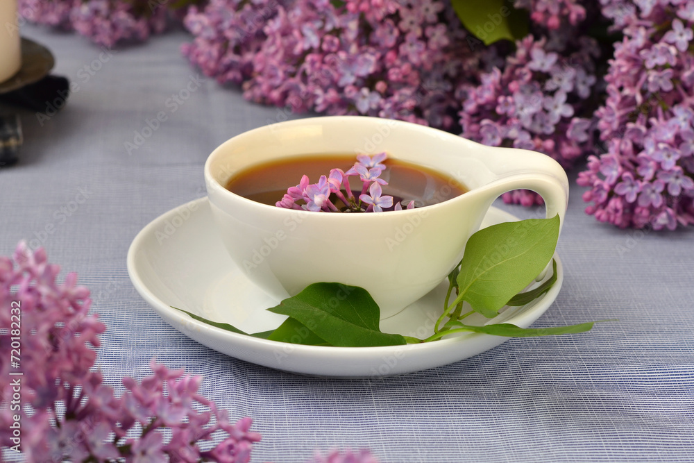 cup with black tea close-up and lilac flowers nearby cup with black tea close-up and lilac flowers nearby