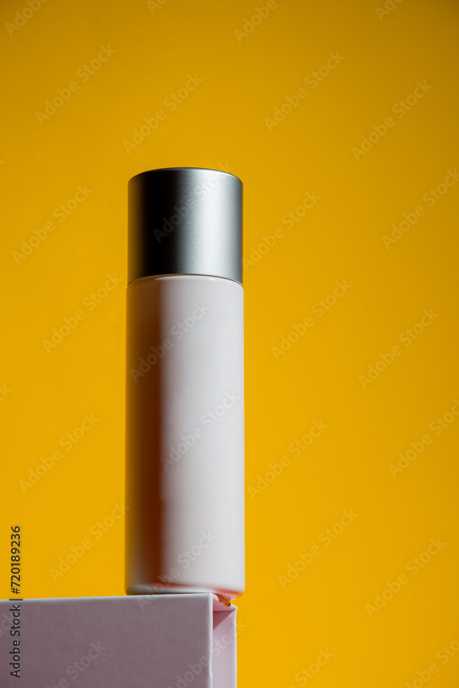 Cosmetic product in tube, bottle, lotion or serum on yellow background Cosmetic product in tube, bottle, lotion or serum on yellow background