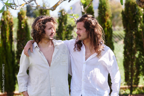 Portrait of caucasian twin brothers in Nature.  Two men with strikingly similar features share a moment of connection amidst lush greenery, exuding a sense of brotherhood and calm. photo