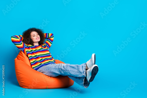 Full body photo of attractive young woman sleeping hands behind head wear trendy rainbow print clothes isolated on blue color background