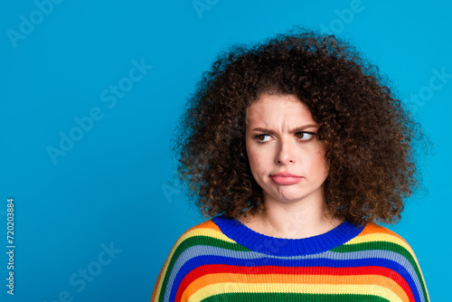 Photo portrait of attractive young woman unhappy look empty space dressed stylish rainbow print clothes isolated on blue color background © deagreez