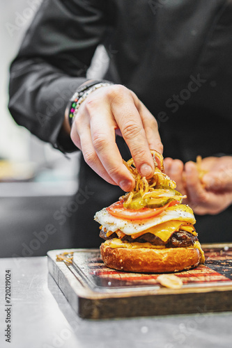 chef hand cooking cheese burger on restaurant kitchen