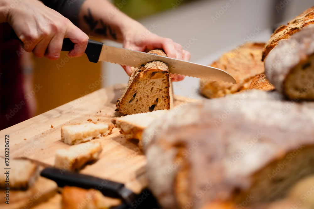 Frisches Brot wird von Bäckerin geschnitten