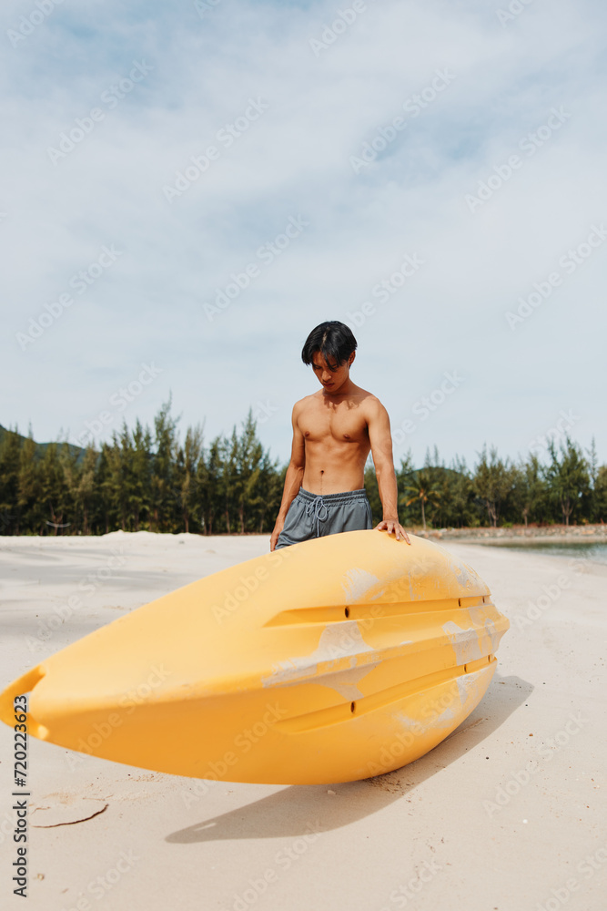 Kayaking Fun: Asian Man Enjoying Active Beach Vacation with Paddle and Canoe in Tropical Paradise
