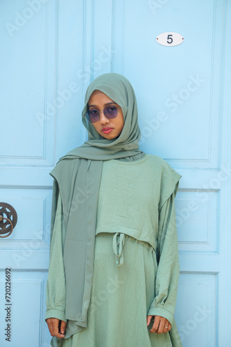 Beautiful Muslim woman wearing a hijab wearing a green dress and glasses
