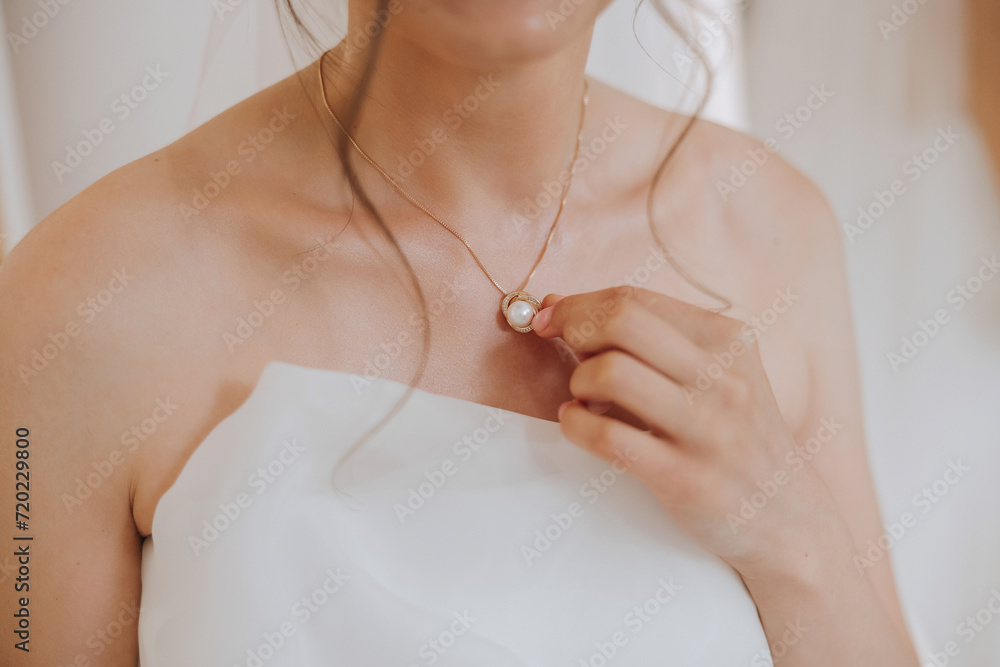 Morning preparation of the bride. Necklace on the neck. Pendant on a gold chain on a woman's breast. Beautiful decollete. Closeup. Morning preparation of the bride. Necklace on the neck. Pendant on a gold chain on a woman's breast. Beautiful decollete. Closeup.