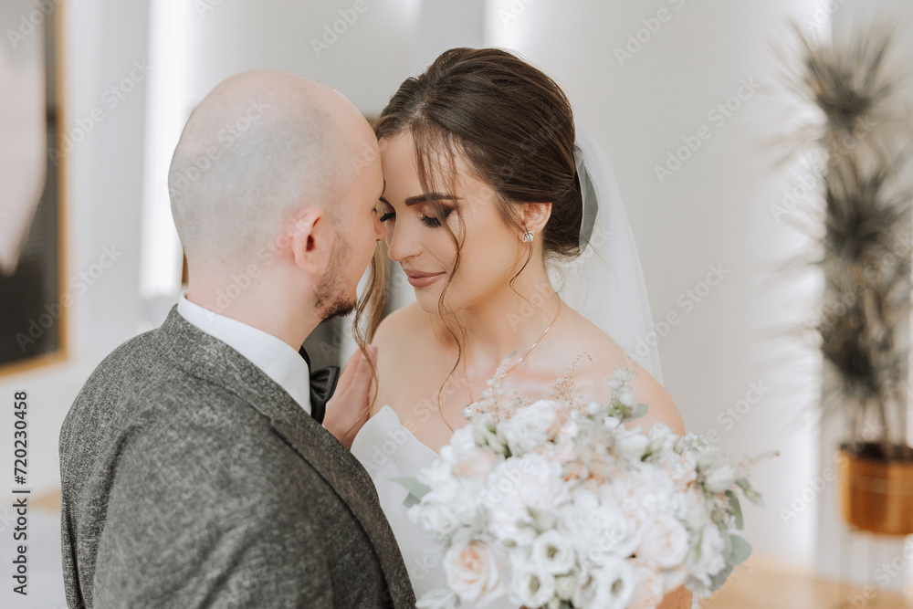 The bride is dressed in an elegant lush white wedding dress with a long veil and is ready for her groom. The first meeting of the bride and groom The bride is dressed in an elegant lush white wedding dress with a long veil and is ready for her groom. The first meeting of the bride and groom