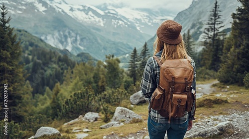 A woman with a backpack gazes at the breathtaking mountains during her hiking adventure.