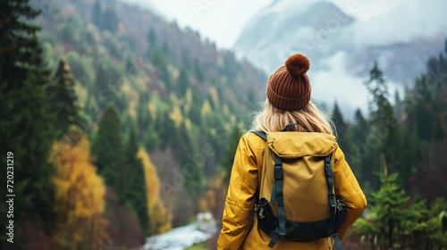 A woman with a backpack gazes at the awe-inspiring beauty of a towering mountain during her adventurous hike.