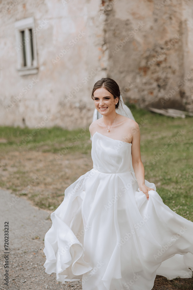 A beautiful bride runs with a long train. The bride in a white dress with a long train in nature on a summer day. Summer wedding.