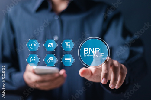 BNPL or Buy Now Pay Later concept, Businessman use smartphone and hand touching virtual BNPL icon with online shopping icons technology.