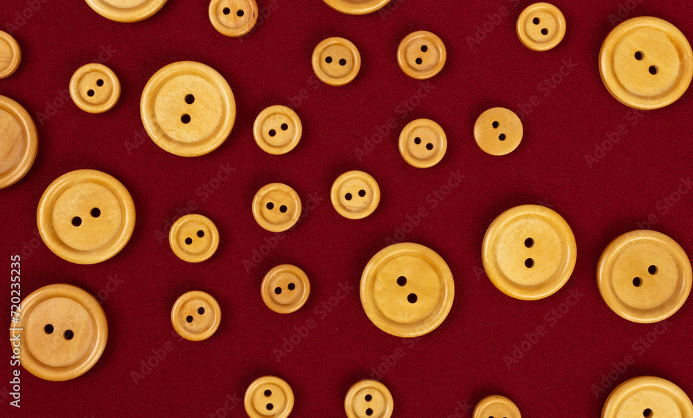 Wooden round buttons different size on a burgundy fabric Wooden round buttons different size on a burgundy fabric