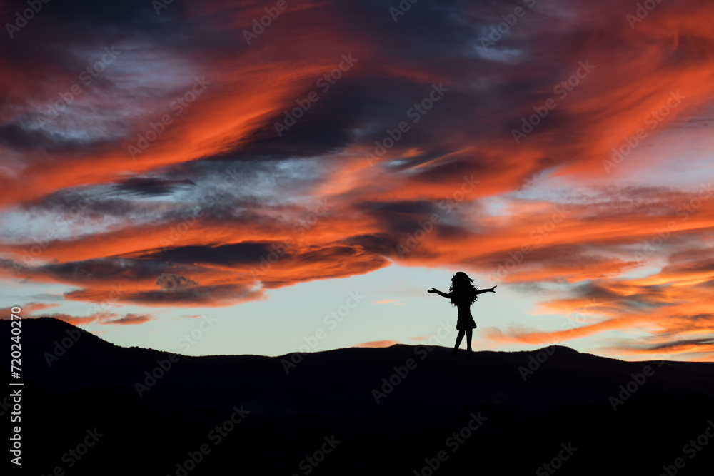 Silhouette of a girl dancing in the landscape at sunset. Nature and happiness.