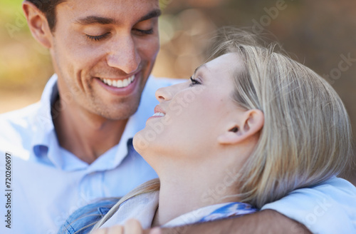 Happy couple, closeup and hug in nature for embrace, love or support in relax for outdoor bonding. Face of young woman and man with smile for affection, comfort or romance in forest or woods together