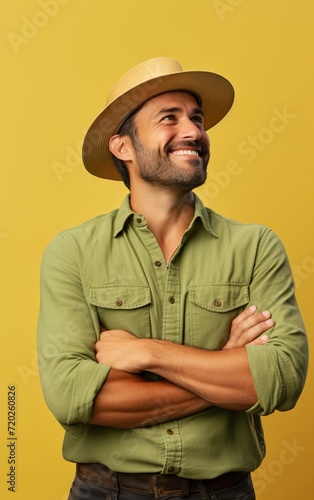 Cheerful man with a wide-brimmed hat looking up, yellow backdrop